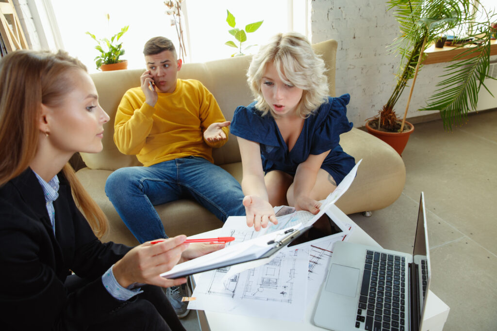 Interior designer working with young couple. Lovely family and professional designer or architector